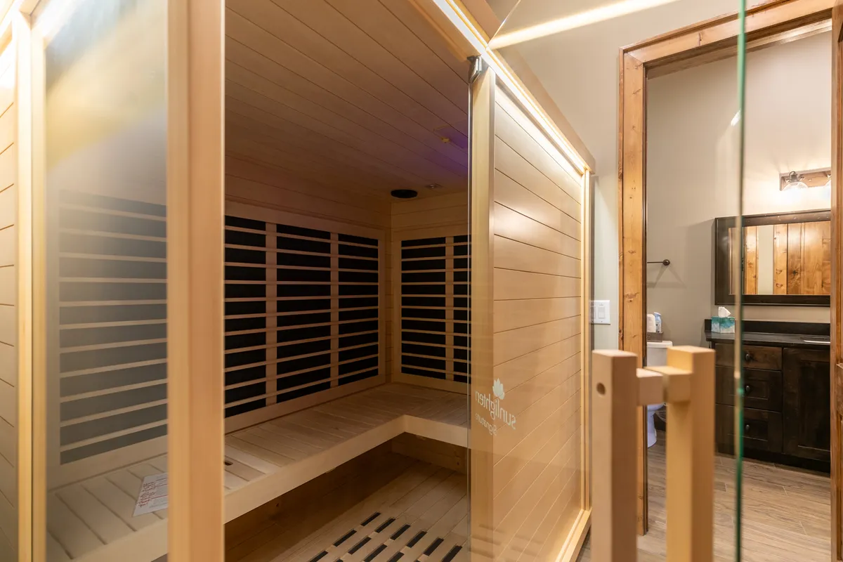 Inside a private dry sauna, the image displays wood paneling and a glass door, creating a serene atmosphere for post-adventure wellness. The space is designed for relaxation and rejuvenation, complementing the active experiences just outside.