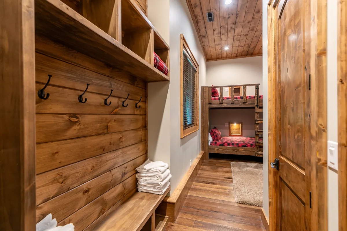 An interior view of a cozy bunk room featuring wooden bunk beds, plaid bedding, soft towels, and a playful, welcoming atmosphere. The space suggests a perfect spot for kids or younger family members to unwind with games, movies, and laughter after outdoor adventures.